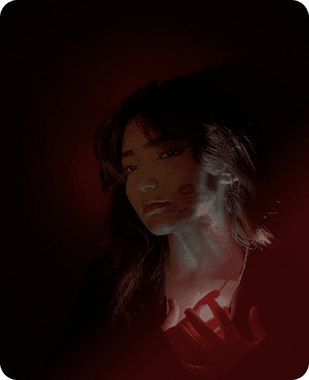 a woman holding a candle in front of a red light